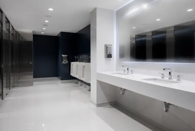 Commercial restroom after a deep clean, chrome fixtures and white tile gleaming
