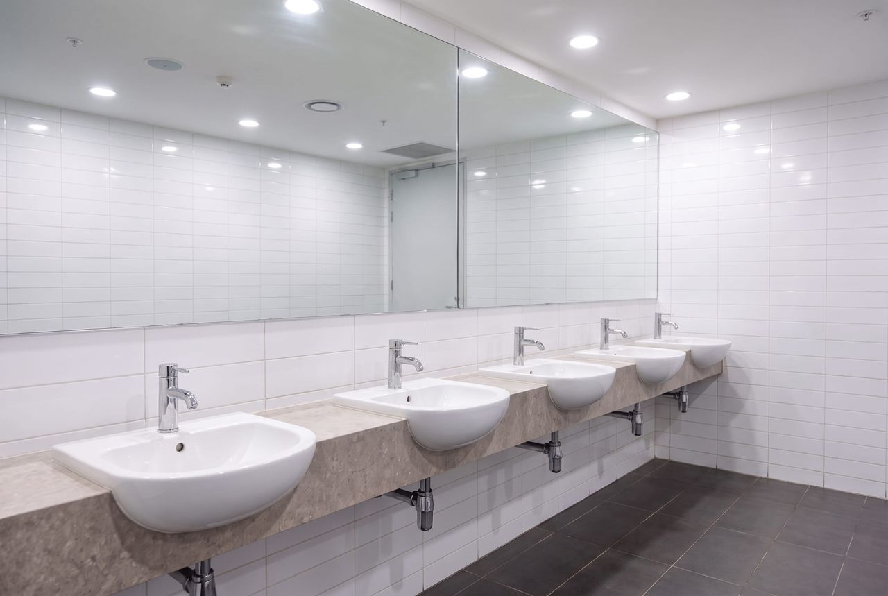 Commercial restroom after a deep clean, chrome polished, mirror clear and grout back to color