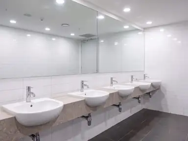Commercial restroom after a deep clean, chrome polished, mirror clear and grout back to color