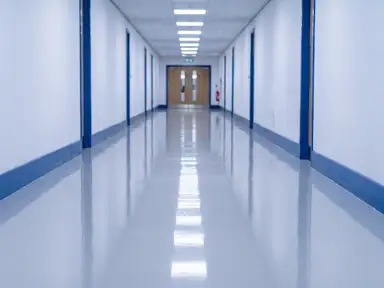 Commercial corridor after a scrubber pass, the vinyl floor mirror-bright from wall to wall