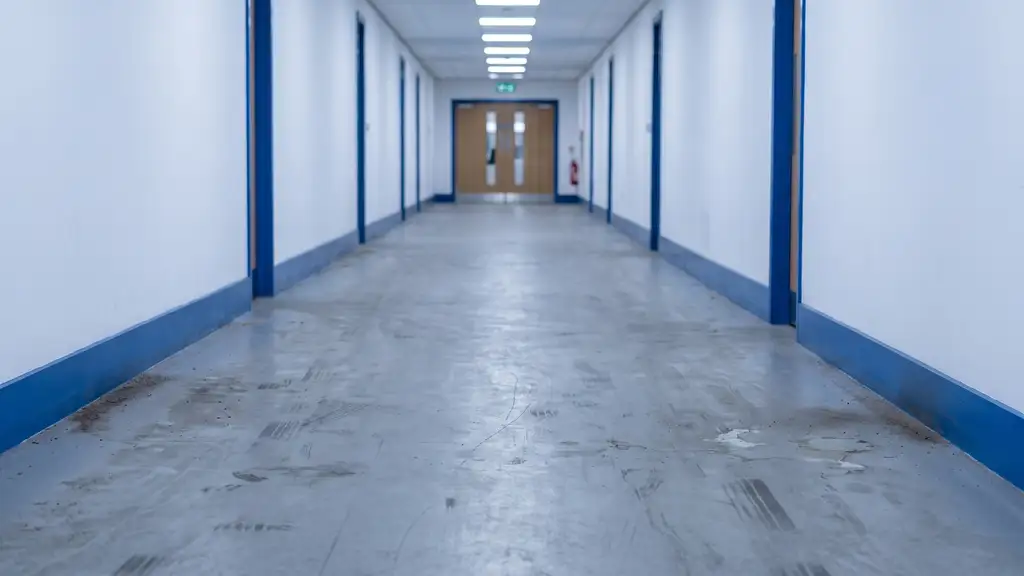 Scuffed and black-marked vinyl corridor floor under raking light before restoration