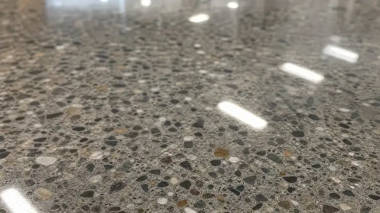 Polished sealed concrete floor reflecting ceiling lights, aggregate visible in the surface