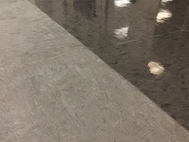 VCT tile floor mid strip-and-wax, stripped bare tile beside new wet gloss finish