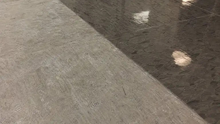 VCT tile floor mid strip-and-wax, stripped bare tile beside new wet gloss finish