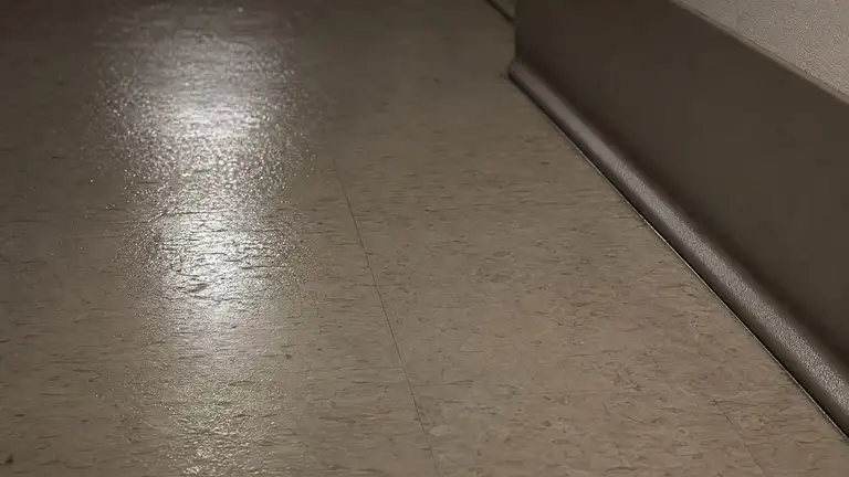 Damp-mopped vinyl corridor floor drying under night lighting in a commercial building