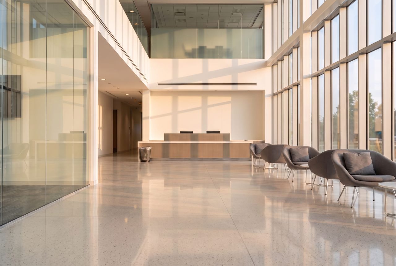 Double-height office lobby after a nightly route, terrazzo polished, glass clear and litter cleared