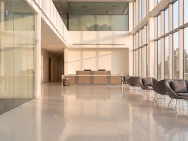 Double-height office lobby after a nightly route, terrazzo polished, glass clear and litter cleared