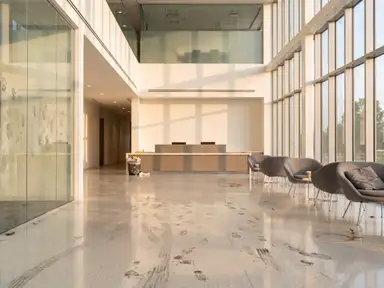 Office lobby at the end of a working day, terrazzo dulled by traffic and litter left on the tables
