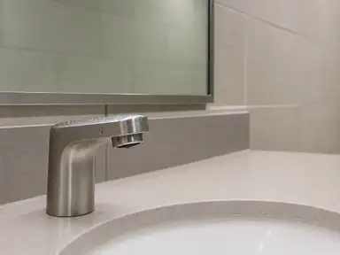 Chrome sensor faucet and spotless counter in a commercial restroom