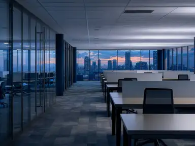 Open-plan office floor after hours, desks cleared under low lighting