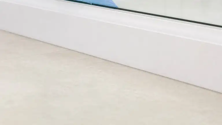 New floor tile and freshly painted baseboard with protective film peeled from glass