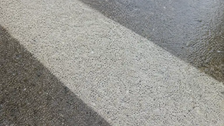 Pressure-washed clean stripe cut across a weathered commercial concrete sidewalk