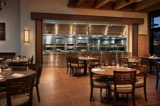 Restaurant dining room and kitchen pass, tables reset and stainless surfaces degreased
