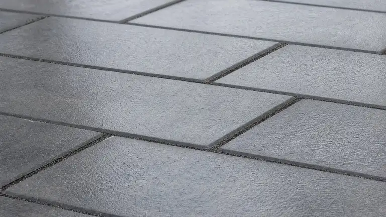 Grey concrete pavers in a running bond under a cured sealer, joints filled flush