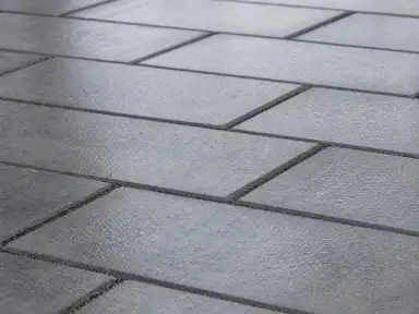 Grey concrete pavers in a running bond under a cured sealer, joints filled flush