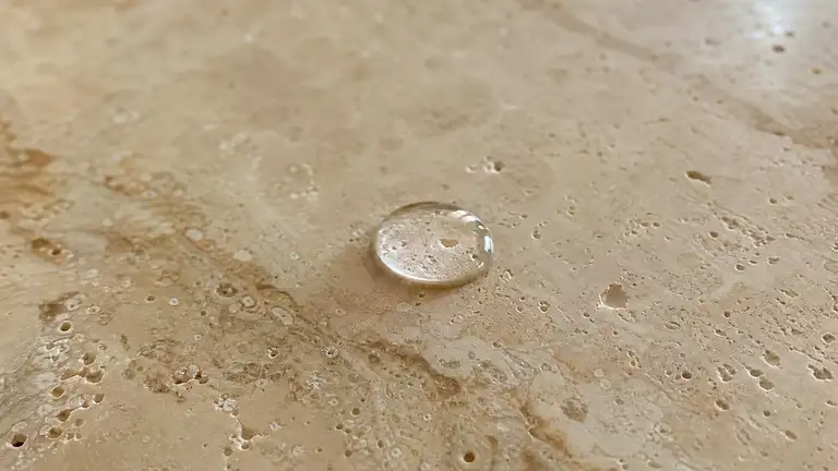 Travertine floor slab under a sealed sheen, natural pitting and veining visible