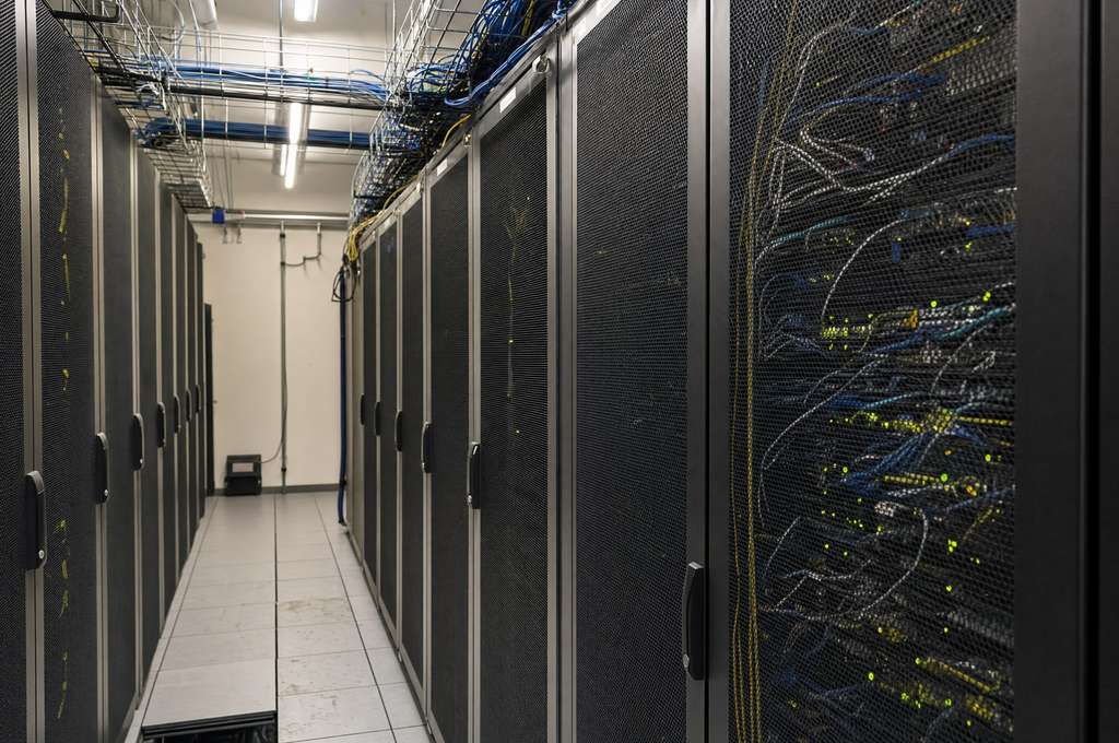Cold aisle between server cabinets, raised access floor swept and cable trays clear of dust