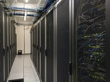 Cold aisle between two rows of server cabinets with overhead cable trays and a raised access floor