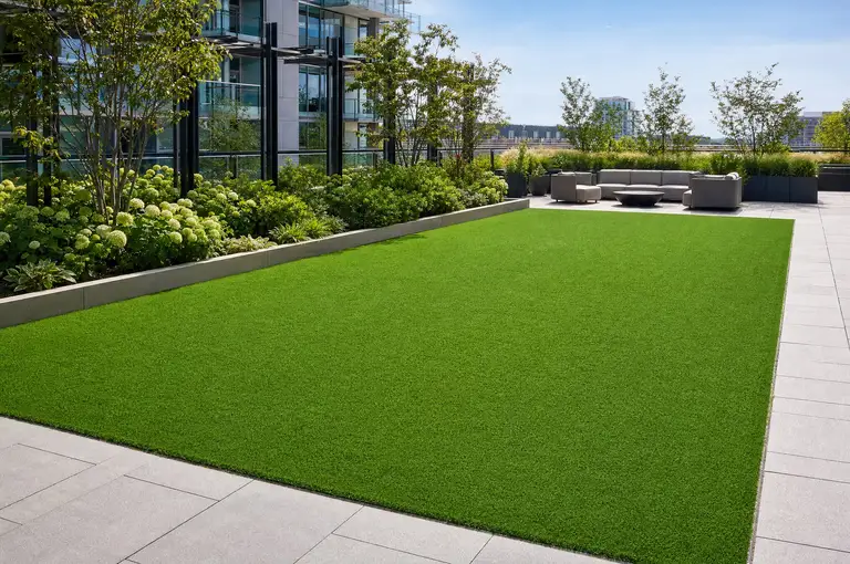 Finished artificial turf on a condominium amenity deck, cut clean against a paver border