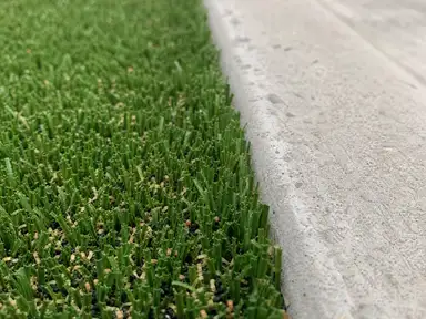 Artificial turf blades meeting a concrete median curb edge